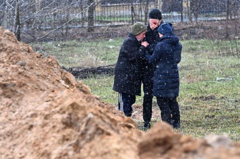 People stand near a mass grave in Bucha, Ukraine on April 3.
