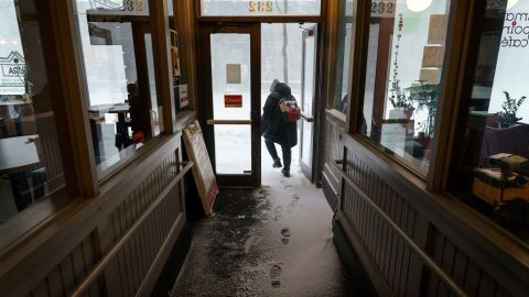 A patron walks through snow in the doorway of a coffee shop in Providence, Rhode Island, on Saturday, January 29. 