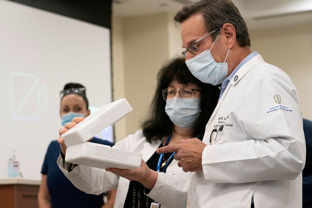 Pharmacy director Dana Rucco, center, shows medical director Dr. Richard Schwarz the container used to deliver the Pfizer-BioNTech Covid-19 vaccine at the Jewish Medical Center in Queens, New York, on December 14.