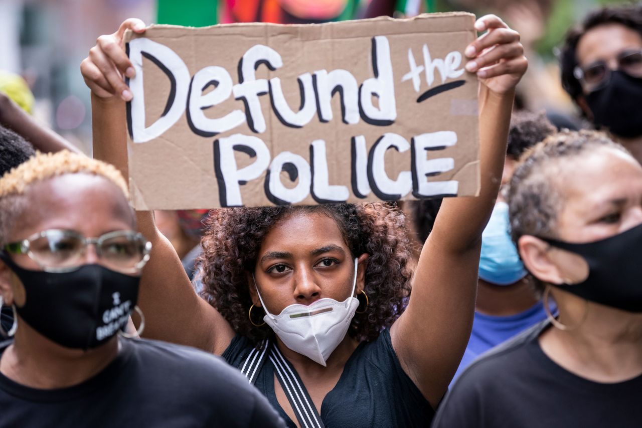 A protester wears a mask and holds a homemade sign that says, "Defund the Police" as they perform a peaceful protest walk across the Brooklyn Bridge in New York on June 19, 2020.