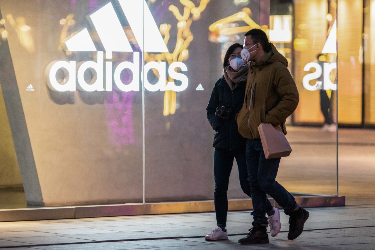 People wearing face masks pass an Adidas story in Beijing on February 1.