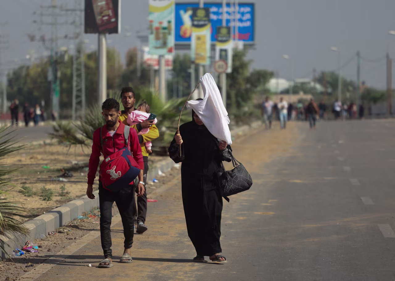A Palestinian woman holds a white flag while evacuating with a group of civilians from the north of Gaza towards the southern region.