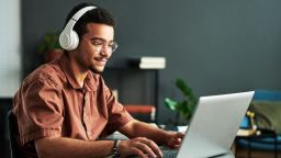 Man happily surfs the web on his laptop.