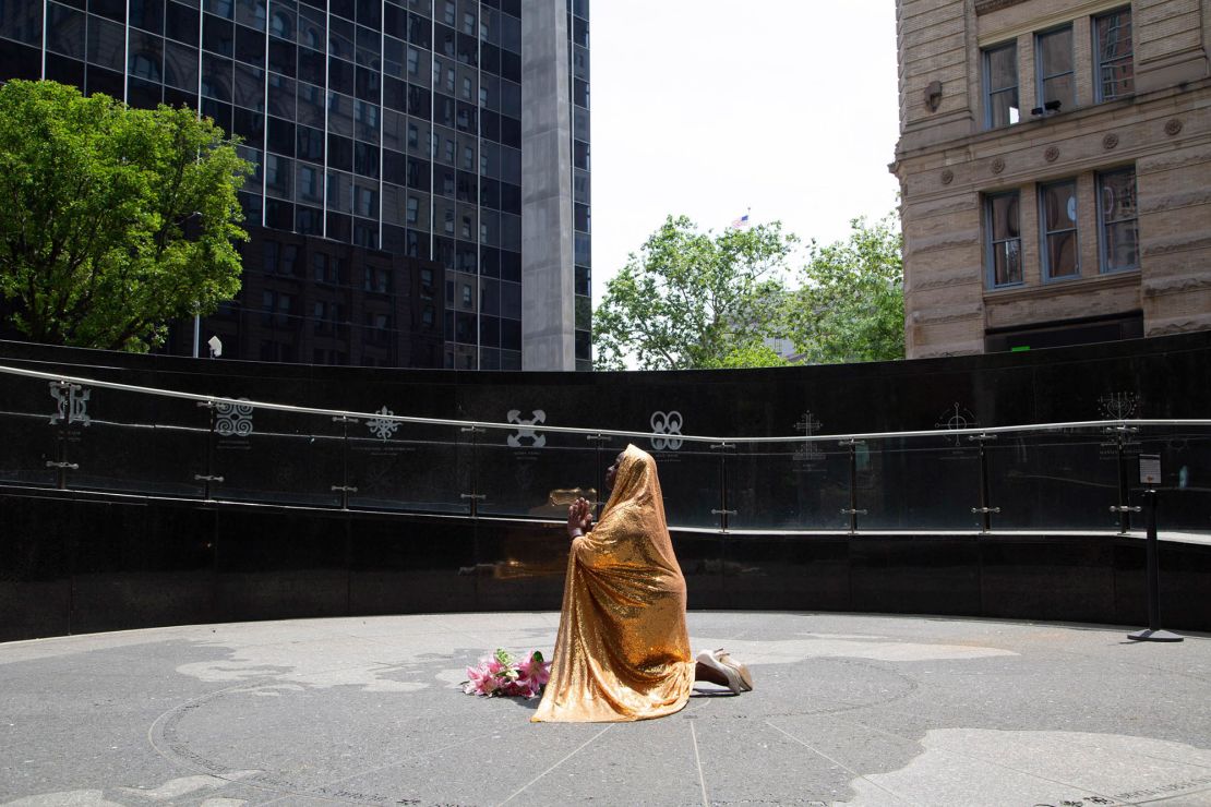A golden cape Faustine wears in photos serves to represent the feminine divine, an energy that promotes positive change in the world and serves to protect sites that carry the legacies of the enslaved. Pictured above, Faustine poses at the African Burial Ground National Monument in downtown Manhattan.