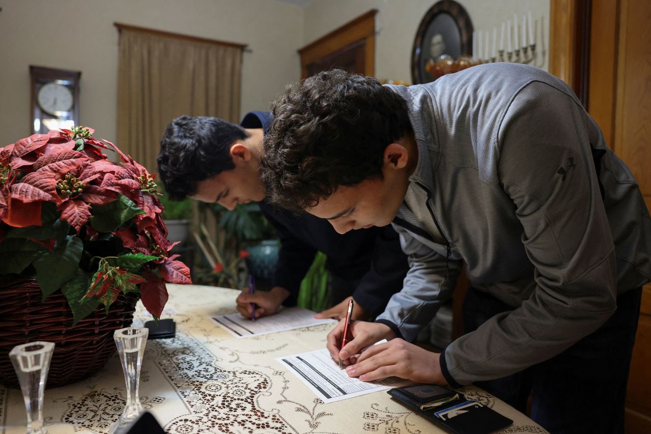 David Gizaw and Nathan Gizaw registers to vote in the Republican presidential caucus at the home of Silver City Mayor Sharon McNutt and her husband Gary, in Silver City on Monday.