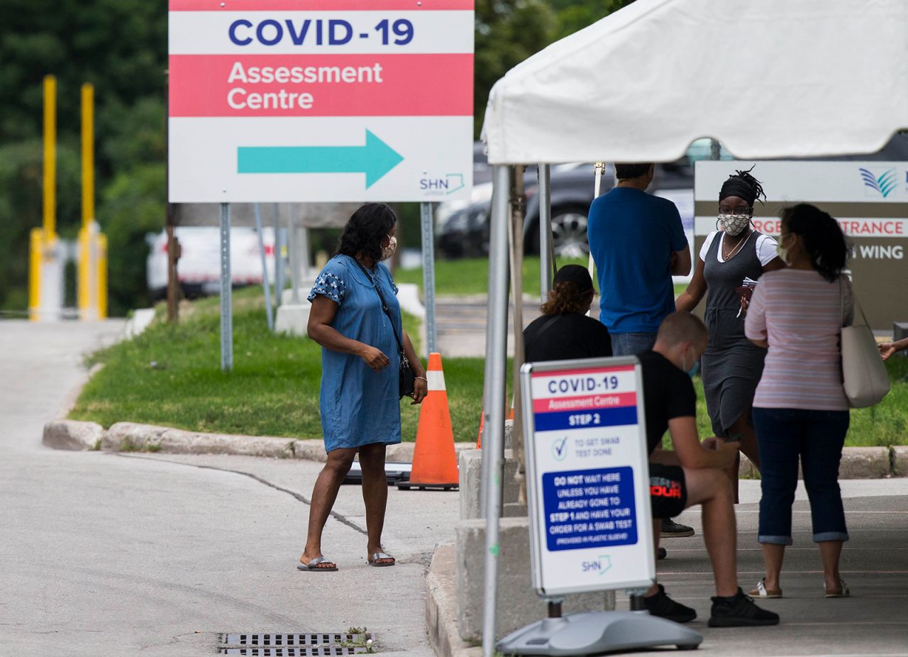 People wearing face masks line up for testing at a Covid-19 assessment center in Toronto, on August 11. 