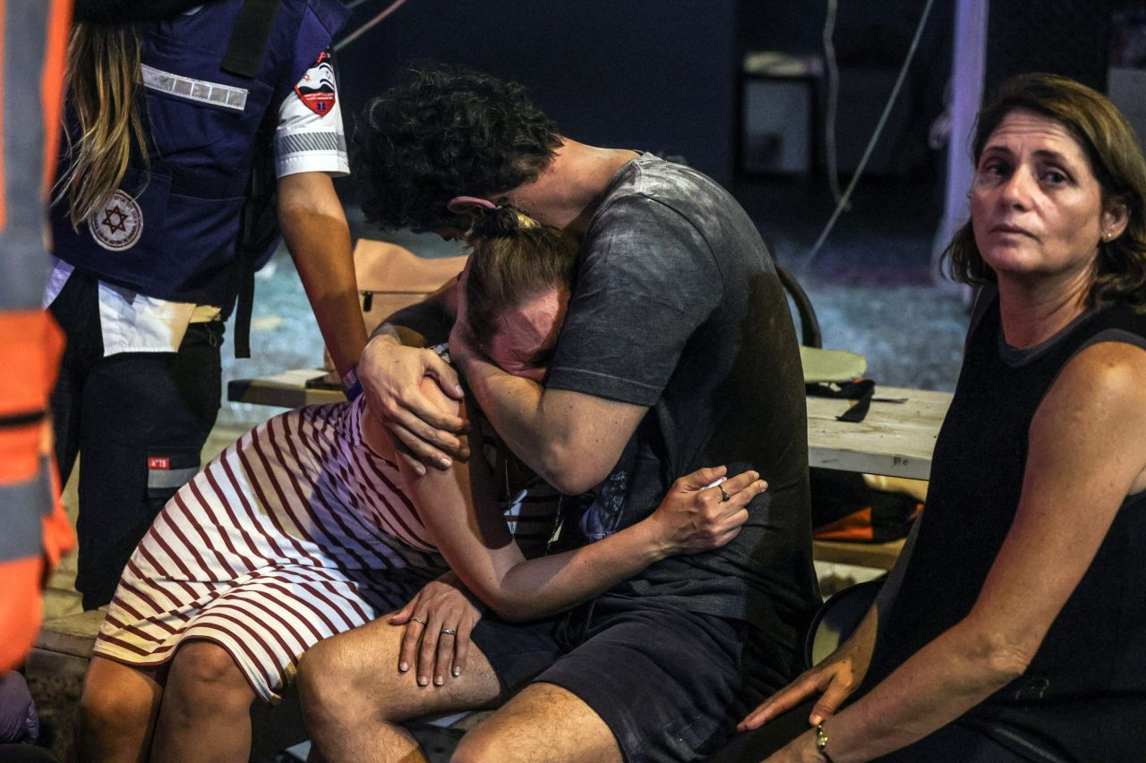 People react at the site where a rocket launched from the Gaza Strip landed in Tel Aviv, Israel, on October 7, 2023.