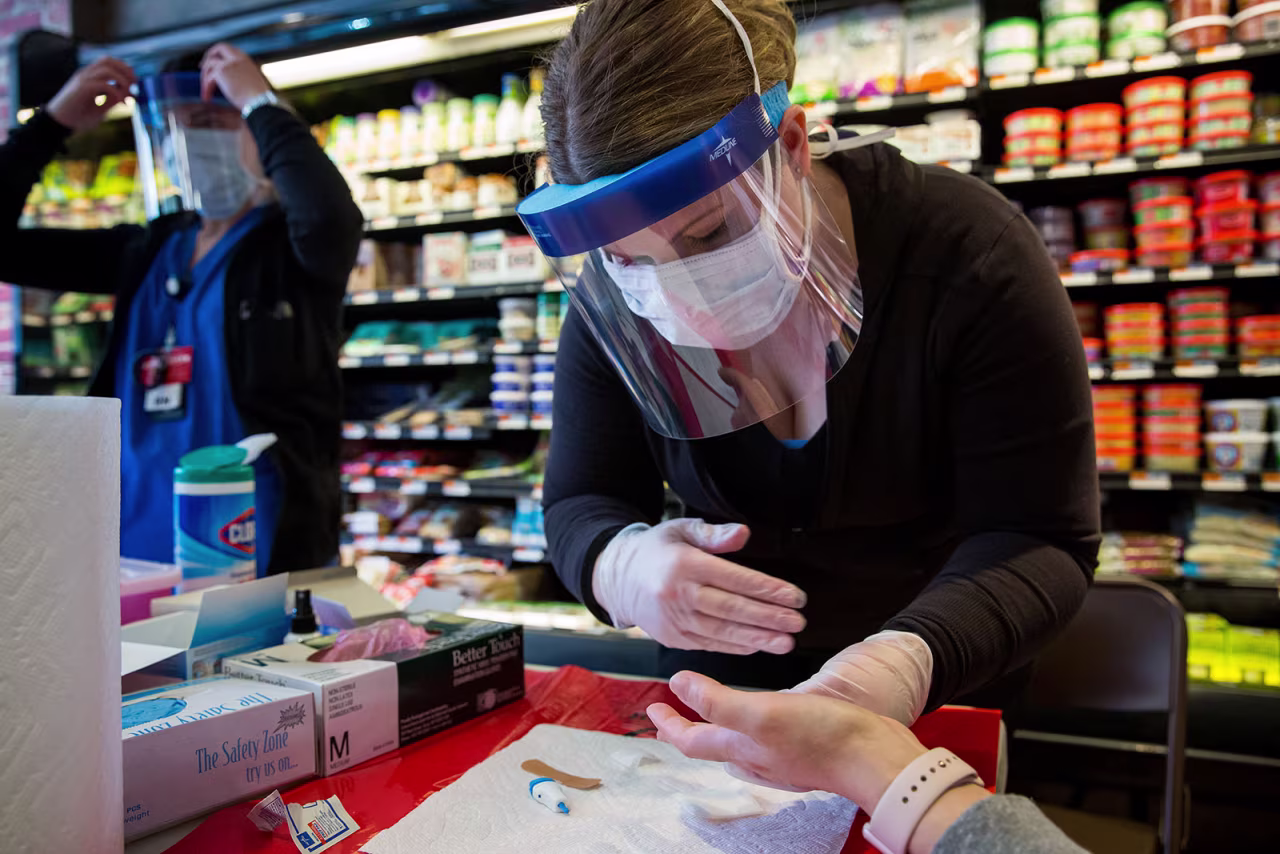 A health care worker performs a Covid-19 antibody test on a woman at Steve's 9th Street Market in Brooklyn, New York, on April 25.