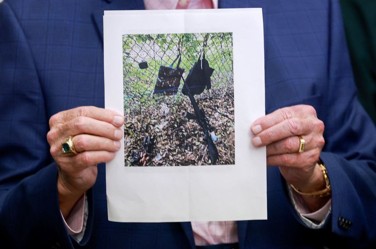 Palm Beach County Sheriff Ric Bradshaw holds a photograph showing a rifle and other items found near where the suspect was discovered Sunday during a press conference in West Palm Beach, Florida. 