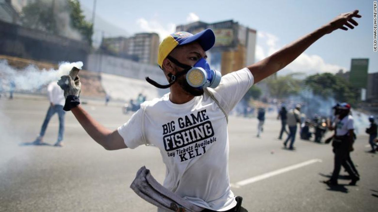 An opposition demonstrator throws back a tear gas canister on a street near the Generalisimo Francisco de Miranda Airbase "La Carlota" in Caracas, Venezuela.