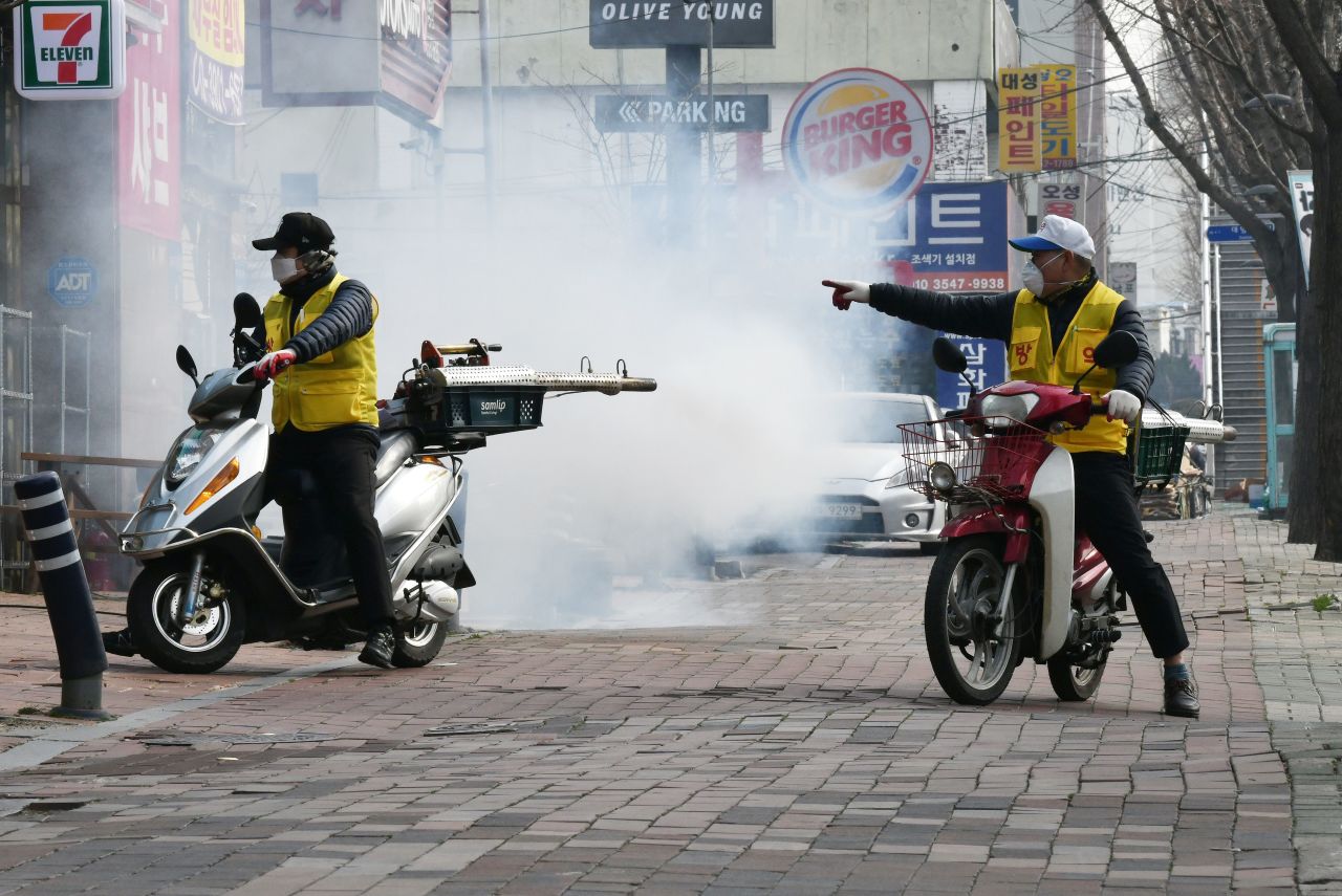 South Korean health officials spray disinfectant in front of the Daegu branch of the Shincheonji religious group in Daegu.