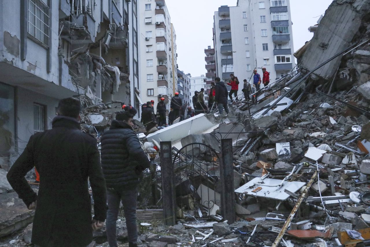 People and rescue teams try to reach trapped residents inside collapsed buildings in Adana, Turkey, on February 6.