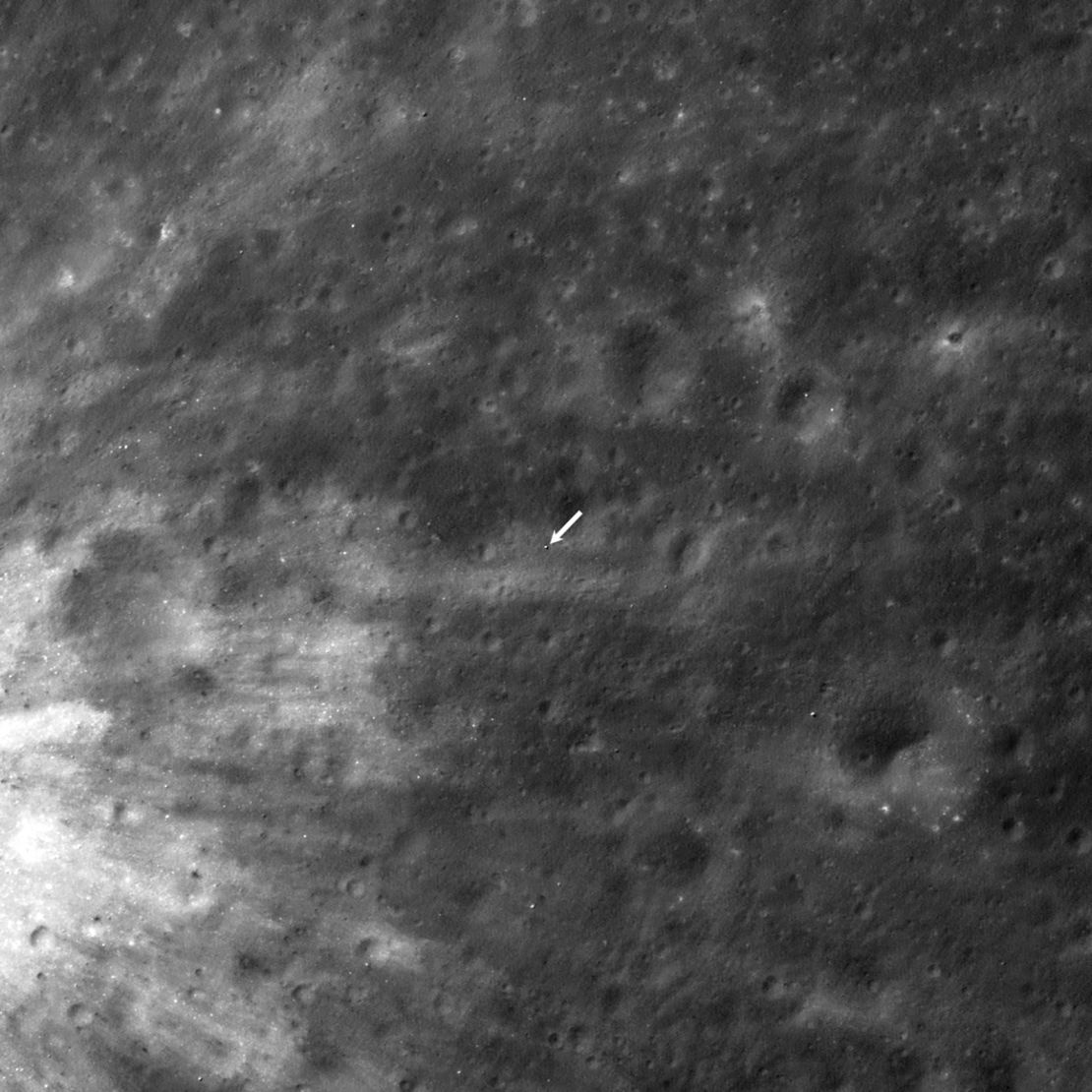 A white arrow points to the location of the SLIM lander on the lunar surface, as imaged by the Lunar Reconnaissance Orbiter.