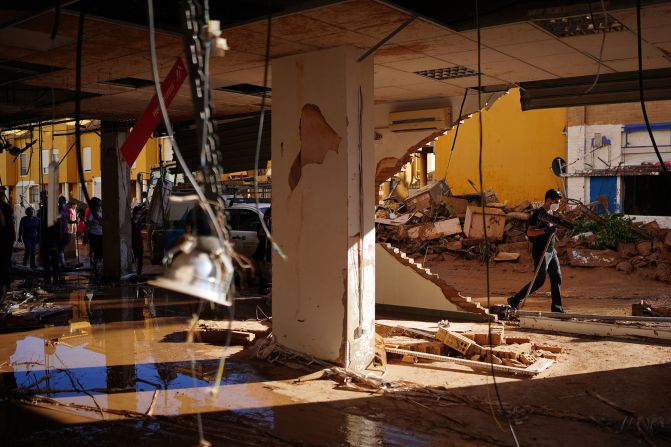 People walk past a damaged hardware store in Benetusser on Saturday.