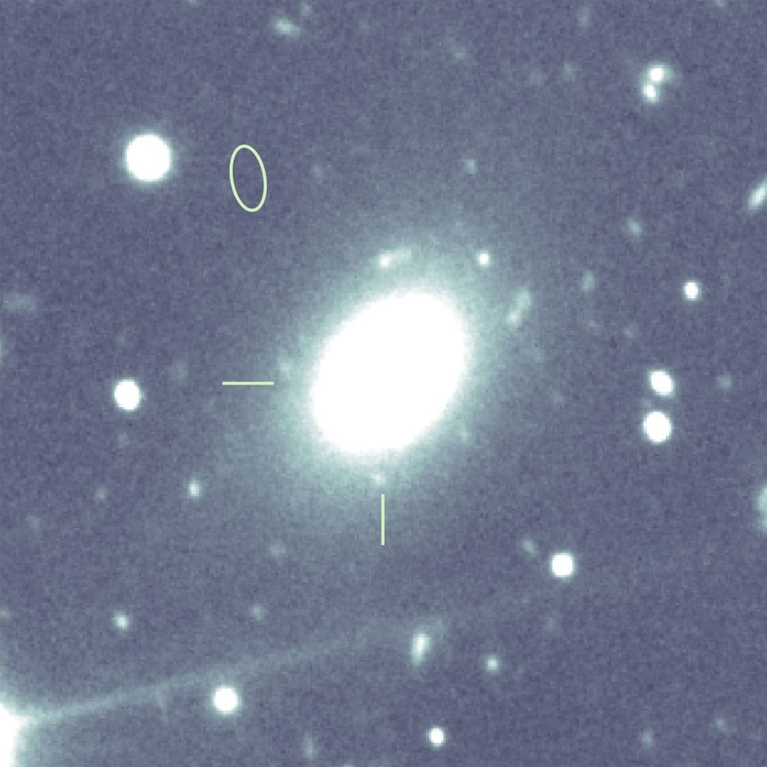 Esta imagen, tomada con un telescopio del Observatorio Gemini de Hawai, muestra a qué distancia se encuentra la ráfaga de radio (marcada con un óvalo) de su galaxia anfitriona (marcada con una cruz).