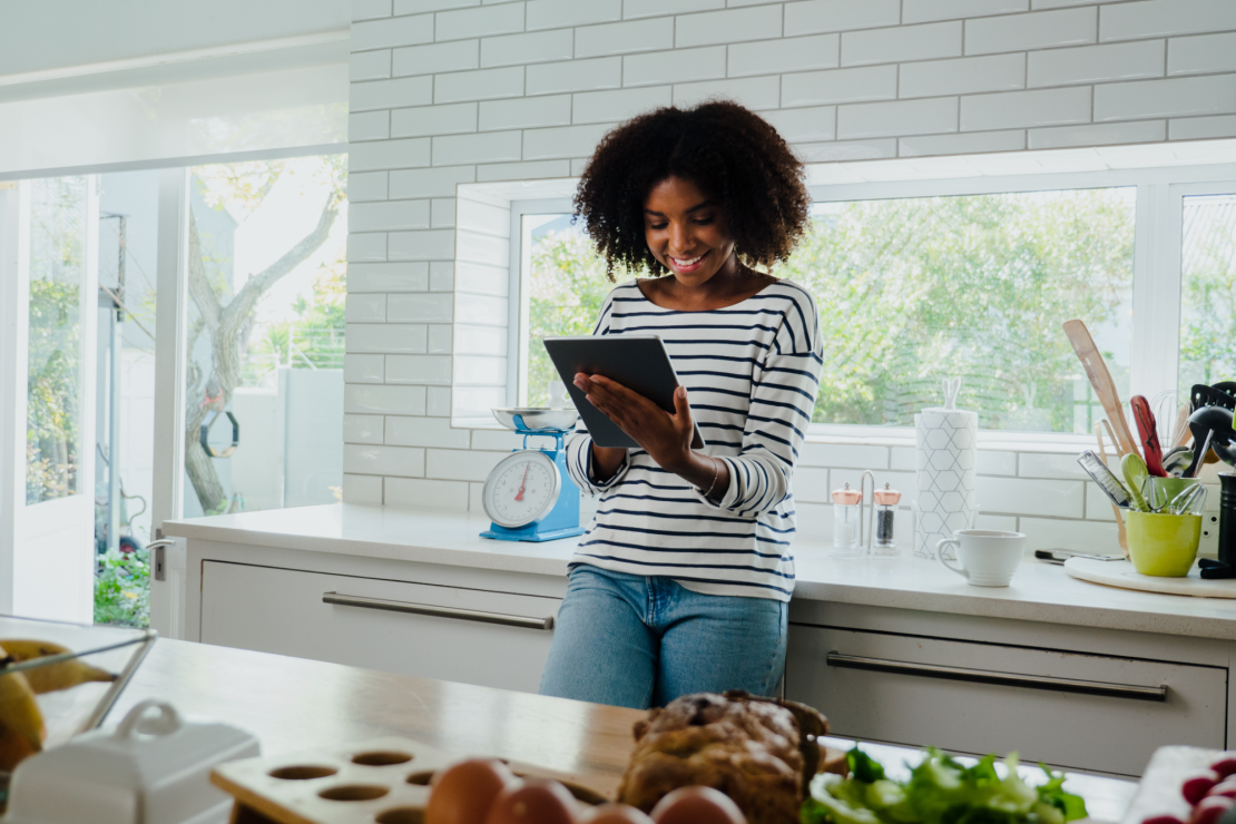 Woman browsing on a tablet in a home kitchen.