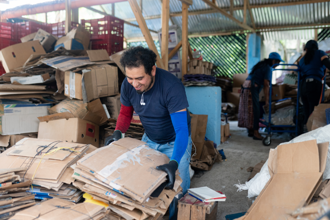 Worker sorting cardboard boxes at recycling center