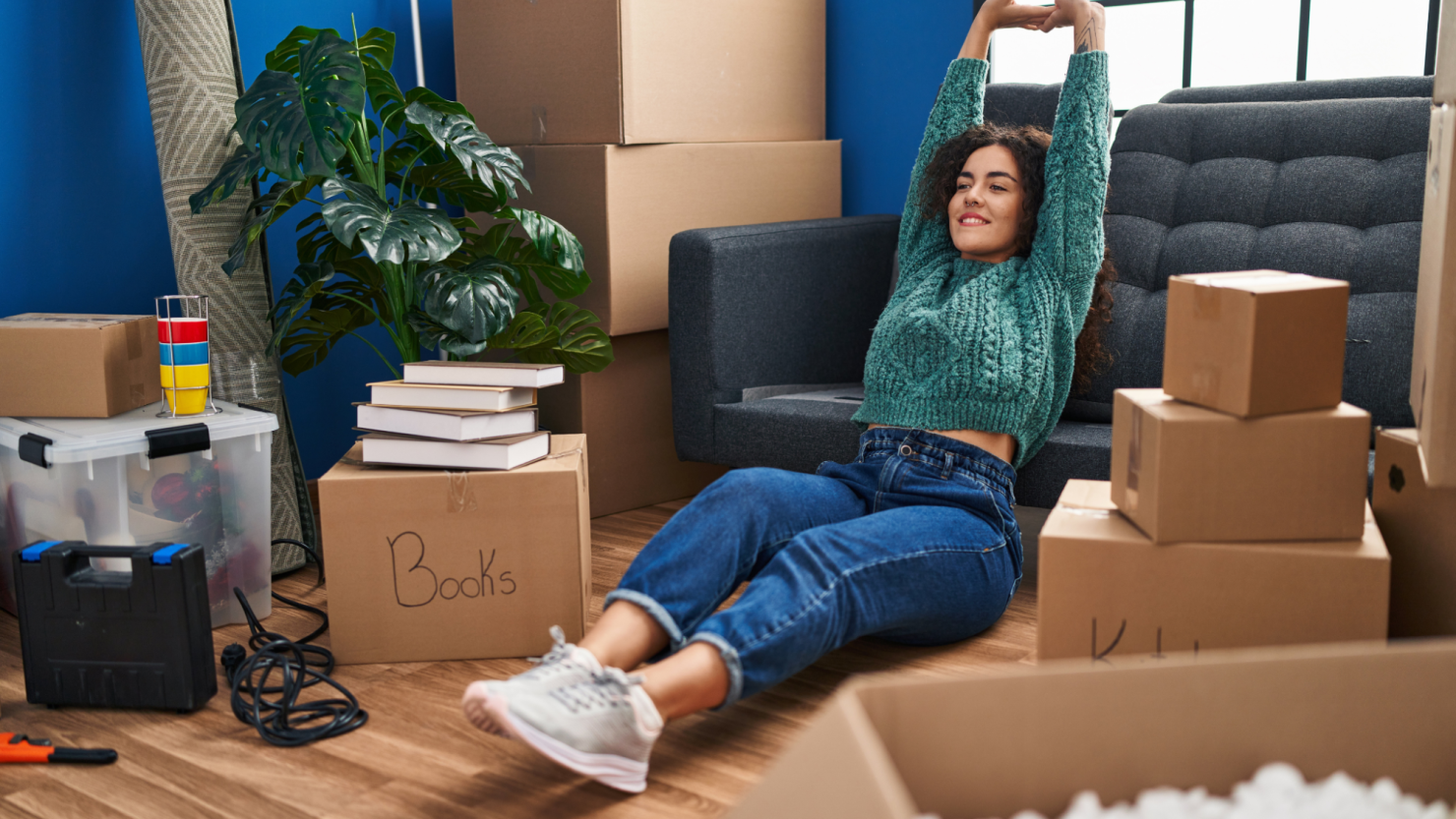 Woman relaxes in a living room amid moving boxes.