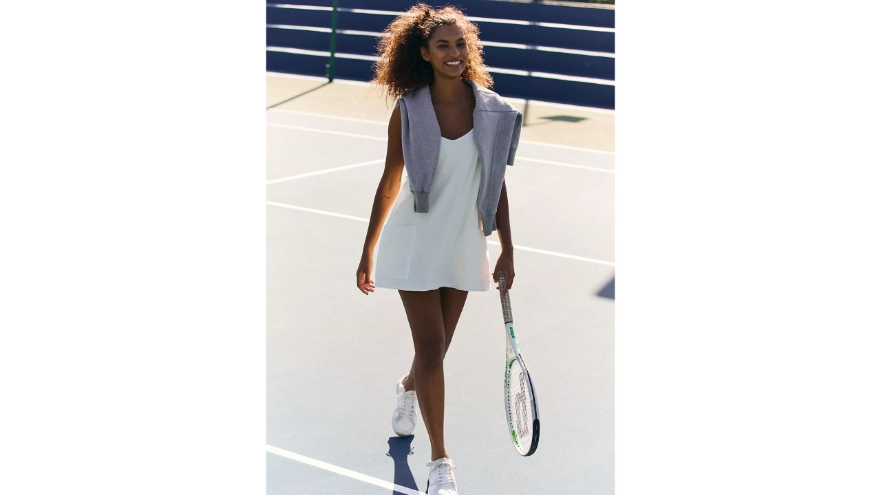 Woman wearing white free people hot shot mini dress while playing tennis