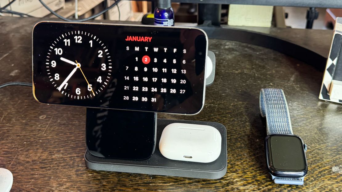 A phone charging on a stand displays a clock and a calendar.