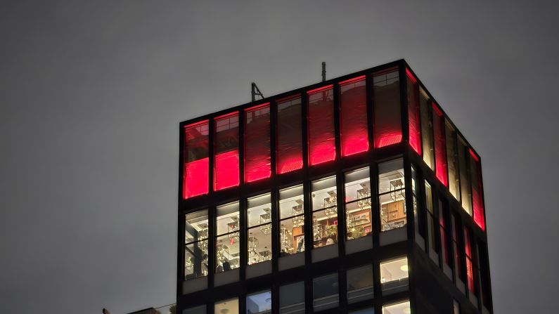 The view of the top of a skyscraper from ground level at night.