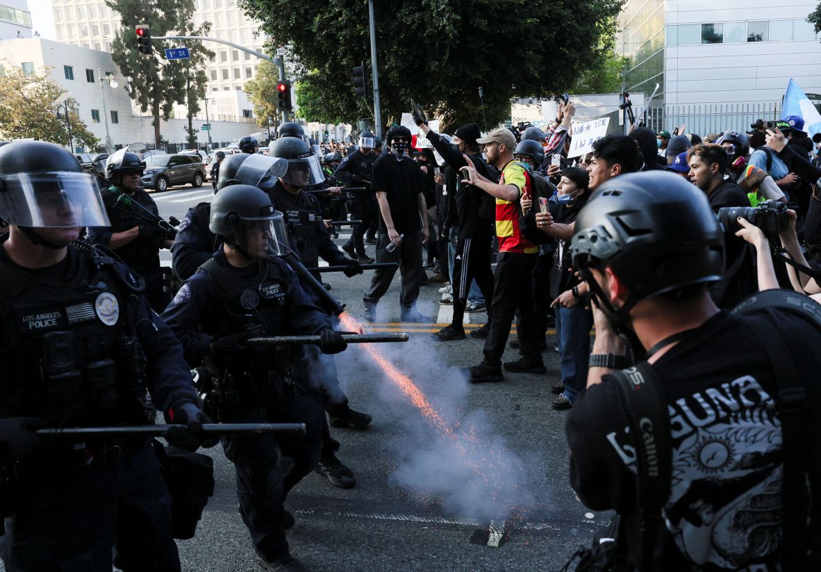 A police officer fires a crowd control munition into the ground while confronting demonstrators on Monday.