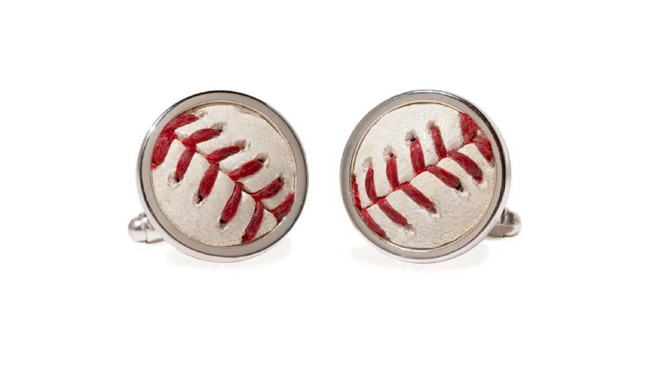 A pair of cufflinks made from baseballs against a white background.