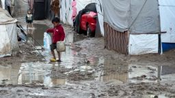 Un niño camina por una carretera inundada entre tiendas de campaña improvisadas en Deir Al-Balah, Gaza, el martes.