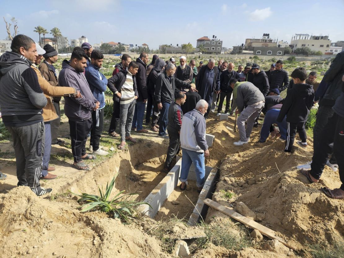 Palestinians gather for the burial of a young girl as Baraka digs her grave.