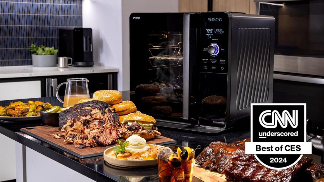 The GE Profile Smart Indoor Smoker is surrounded by barbecue food and drink.