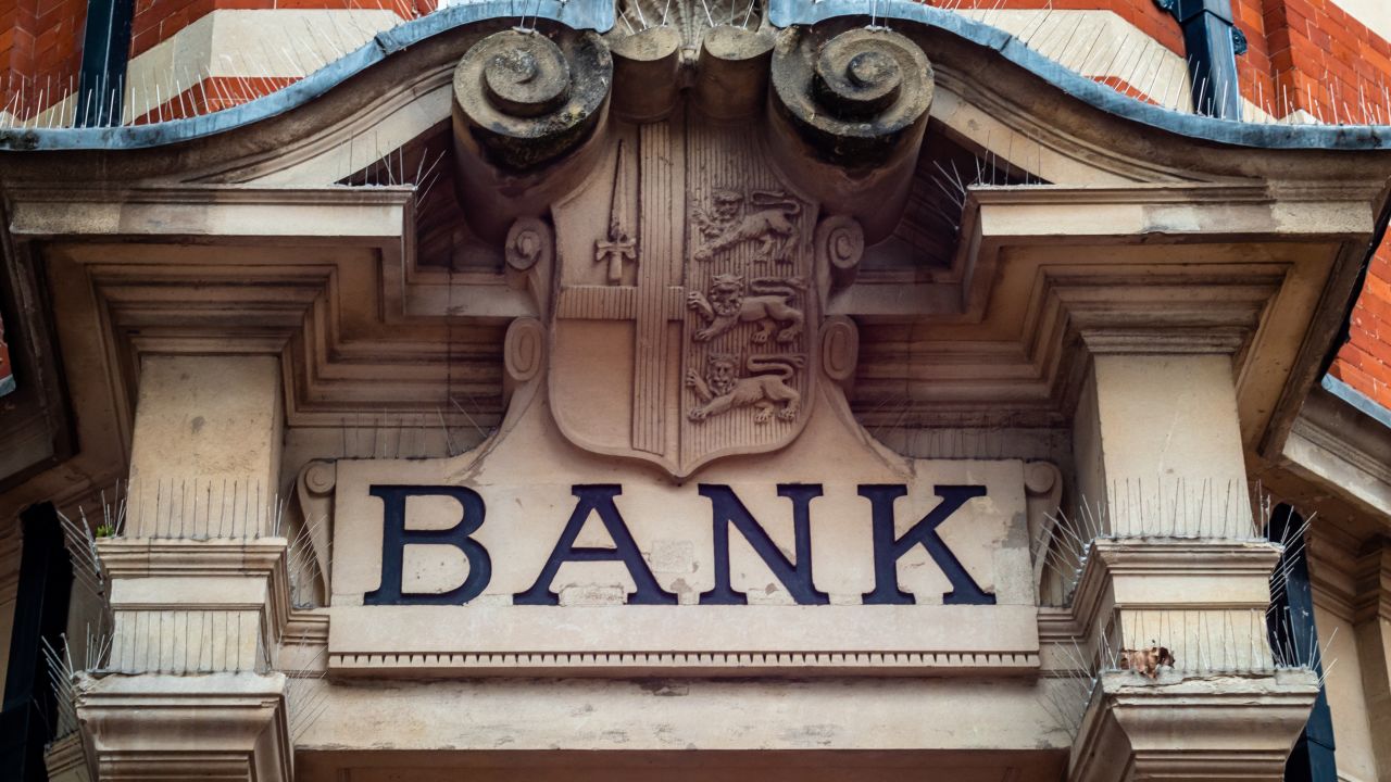 A sign that reads "Bank" on the outside of an older building.