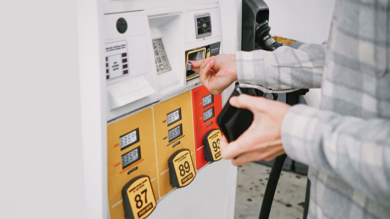Person holding a wallet and putting a credit card into a gas pump.