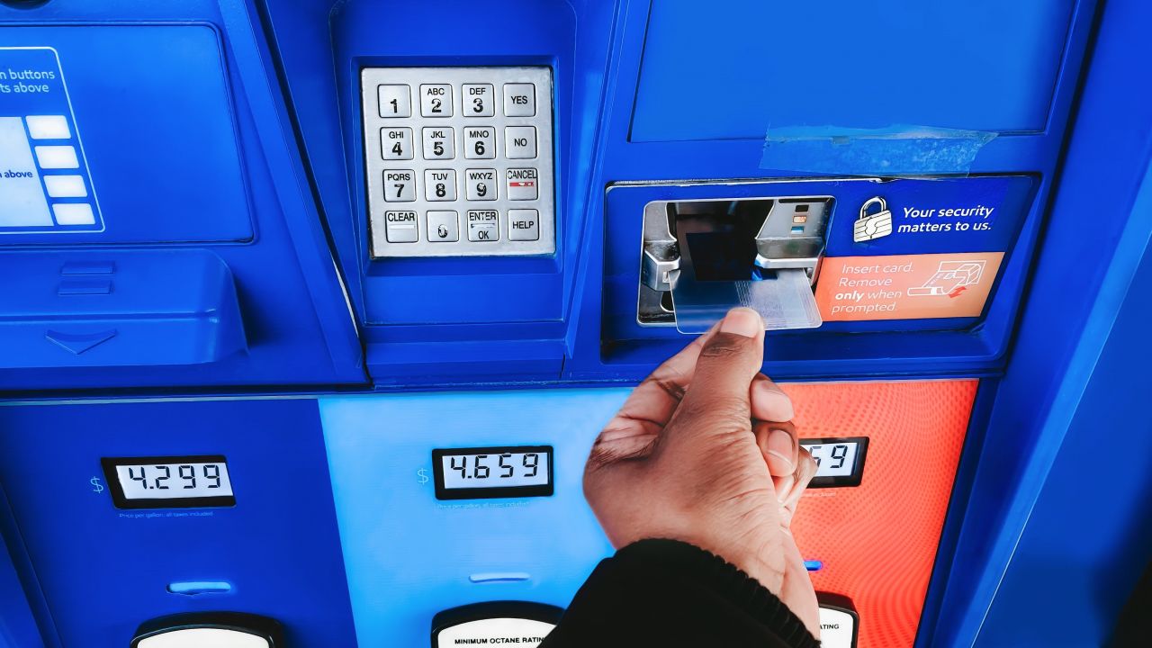 Hand putting credit card in a gas pump.