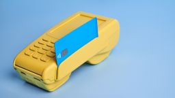 A blue credit card in a yellow credit card terminal.
