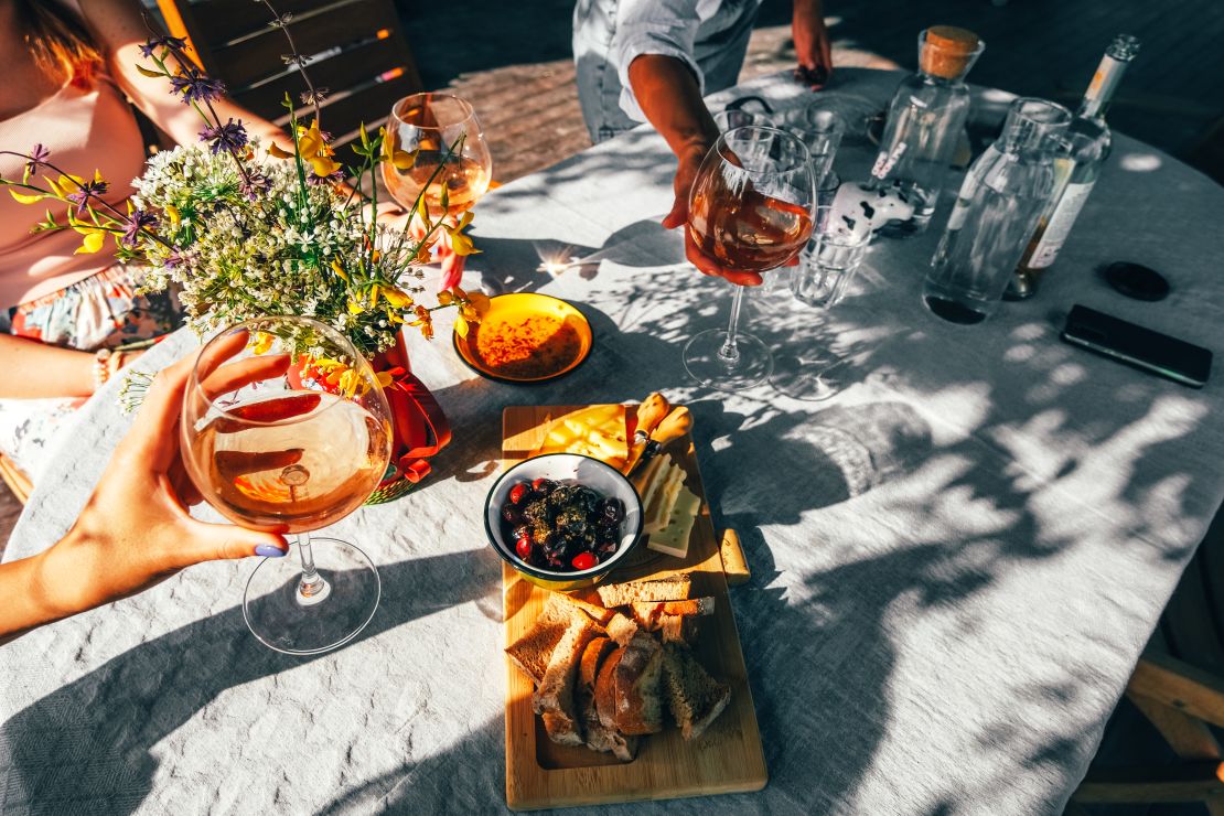 Wine glasses and food on a table outside.