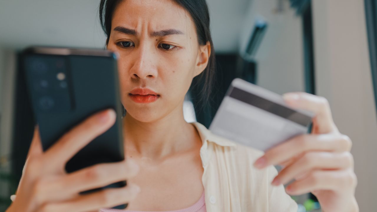 Person looking at a credit card and a cell phone.