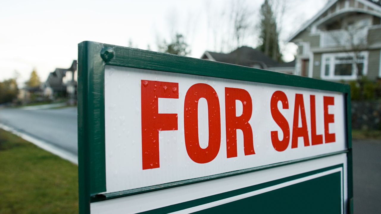 A for sale sign in front of a suburban home.