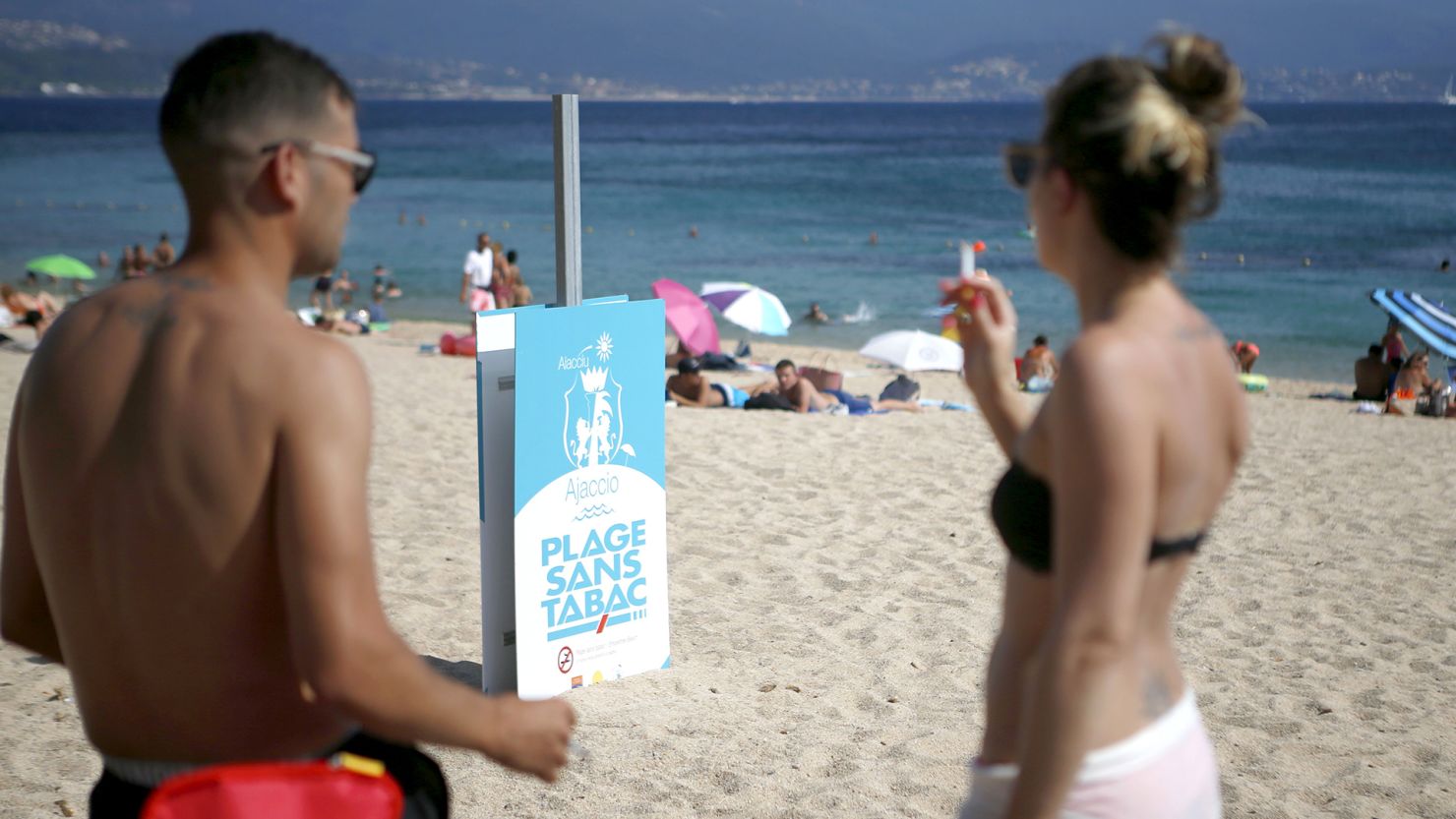 A man and woman smoke cigarettes by a non-smoking beach in Ajaccio, on the French Mediterranean island of Corsica.