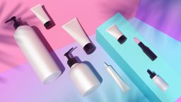 Trendy realistic mock up of cosmetics bottles, tubes and pink lipstick from top view. Modern bright flat lay still life bundle. 3d illustration. Palm leaves shadows. Skin or hair care.