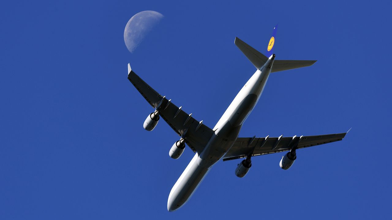 An airplane of Lufthansa, type Airbus A340, flies past the moon in a blue sky during its landing approach in Essen, Germany, 25 August 2016. Photo: Federico Gambarini/dpa | usage worldwide   (Photo by Federico Gambarini/picture alliance via Getty Images)