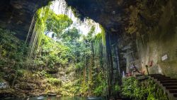 CHICHEN ITZA, MEXICO - SEPTEMBER 29:  Tourists enjoys the Cenote Ik Kil outside of Chichen Itza, Mexico. Cenotes are massive sinkholes formed when the ceiling of a cave collapses underwater, creating a network of underwater caverns in crystal clear water that divers come from around the world to explore. In ancient times, cenotes served as the Mayan civilizations only source of water and were also held as being sacred to the Mayan People. They believed that the sinkholes represented a passage to the underworld, or "Xibalba in the Mayan language. Archaeologists have found fossils of mammoths, massive jaguars, and sloths in these underground cave systems, as well as human bones indicating ritual sacrifice and human presence in the cenotes as far back as 9,000 years ago. (Photo by Donald Miralle/Getty Images for Lumix)