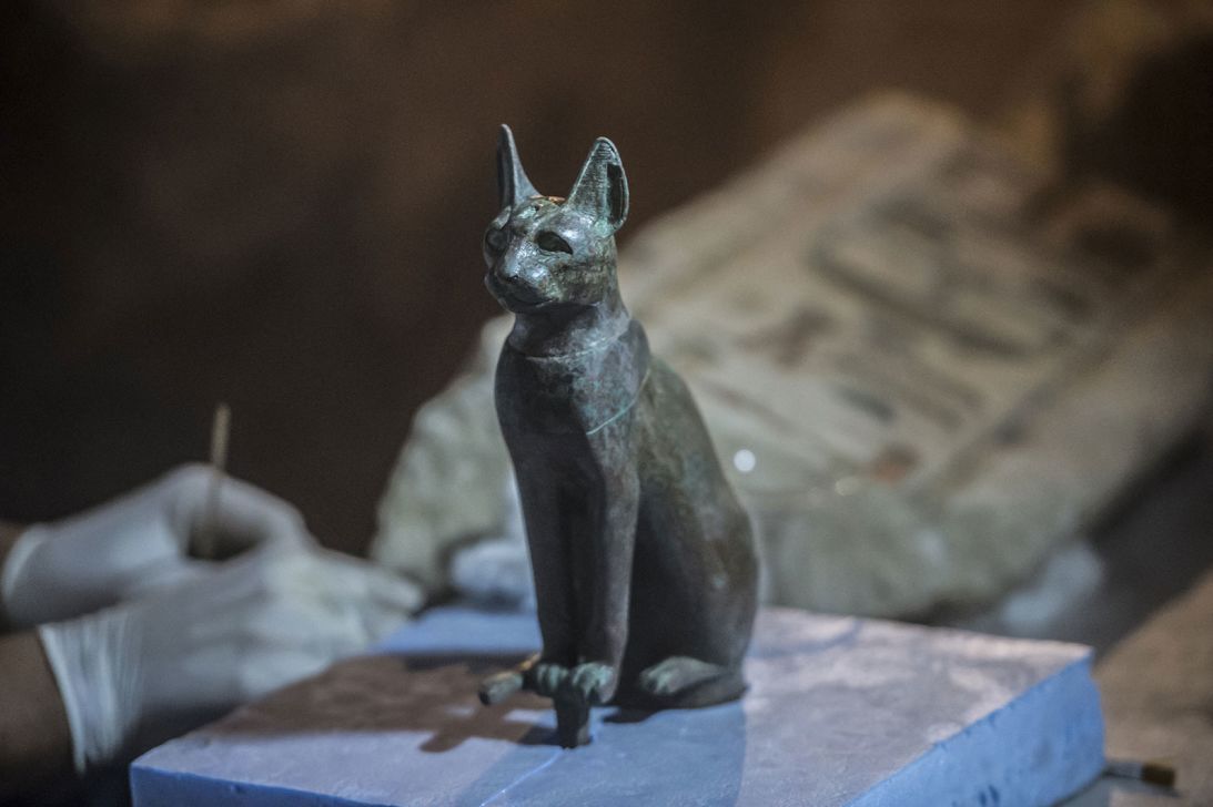 An Egyptian archaeologist cleans an ancient Egyptian sitting cat statue in the Saqqara Necropolis, south of Cairo, on November 10, 2018.