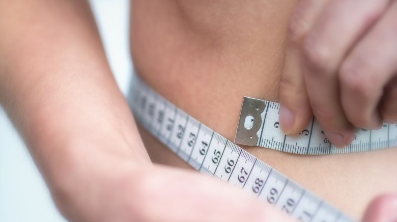 Woman measures very thin waist with measuring tape
