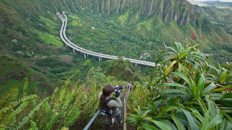 A woman takes pictures as she hikes the Stairway to Heaven, also known as Haiku Stairs on Oahu, Hawaii.