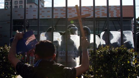 An opposition protester shows the Nicaraguan Constitution to riot police from a shopping mall where he and others took refuge after they were prevented by the police from demonstrating against the government to demand the release of those arrested for taking part in anti-government protests, in the surroundings of the Centroamerica roundabout in Managua on March 16, 2019. - Nicaragua on Friday released 50 prisoners held for participating in anti-government protests, giving a fresh impetus to peace talks on ending the country's long running political crisis. More than 700 people were detained during a deadly crackdown on rallies that began last April and quickly grew into broad opposition to President Daniel Ortega iron-fisted rule. (Photo by Maynor Valenzuela / AFP)        (Photo credit should read MAYNOR VALENZUELA/AFP via Getty Images)