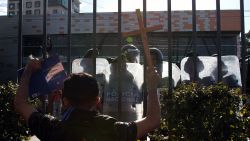 An opposition protester shows the Nicaraguan Constitution to riot police from a shopping mall where he and others took refuge after they were prevented by the police from demonstrating against the government to demand the release of those arrested for taking part in anti-government protests, in the surroundings of the Centroamerica roundabout in Managua on March 16, 2019. - Nicaragua on Friday released 50 prisoners held for participating in anti-government protests, giving a fresh impetus to peace talks on ending the country's long running political crisis. More than 700 people were detained during a deadly crackdown on rallies that began last April and quickly grew into broad opposition to President Daniel Ortega iron-fisted rule. (Photo by Maynor Valenzuela / AFP)        (Photo credit should read MAYNOR VALENZUELA/AFP via Getty Images)