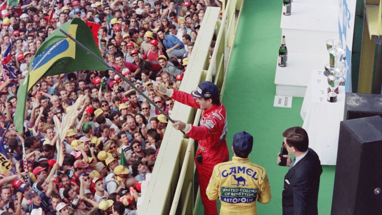 Brazilian Formula One driver Ayrton Senna (McLaren-Honda) holds a Brazilian flag and waves to the crowd after the Italian Grand Prix in Monza, 13 September, 1992. - Senna won the race with Martin Brundle (Benetton-Cosworth) second and Michael Schumacher (Camel ad, Benetton-Cosworth) third. It was the thirteenth round of the 1992 Formula One season. In 1991, Ayrton Senna became the World Driving Champion for the third and last time of his career. (Photo by Pascal PAVANI and Jean-Loup GAUTREAU / AFP) (Photo by PASCAL PAVANI,JEAN-LOUP GAUTREAU/AFP via Getty Images)