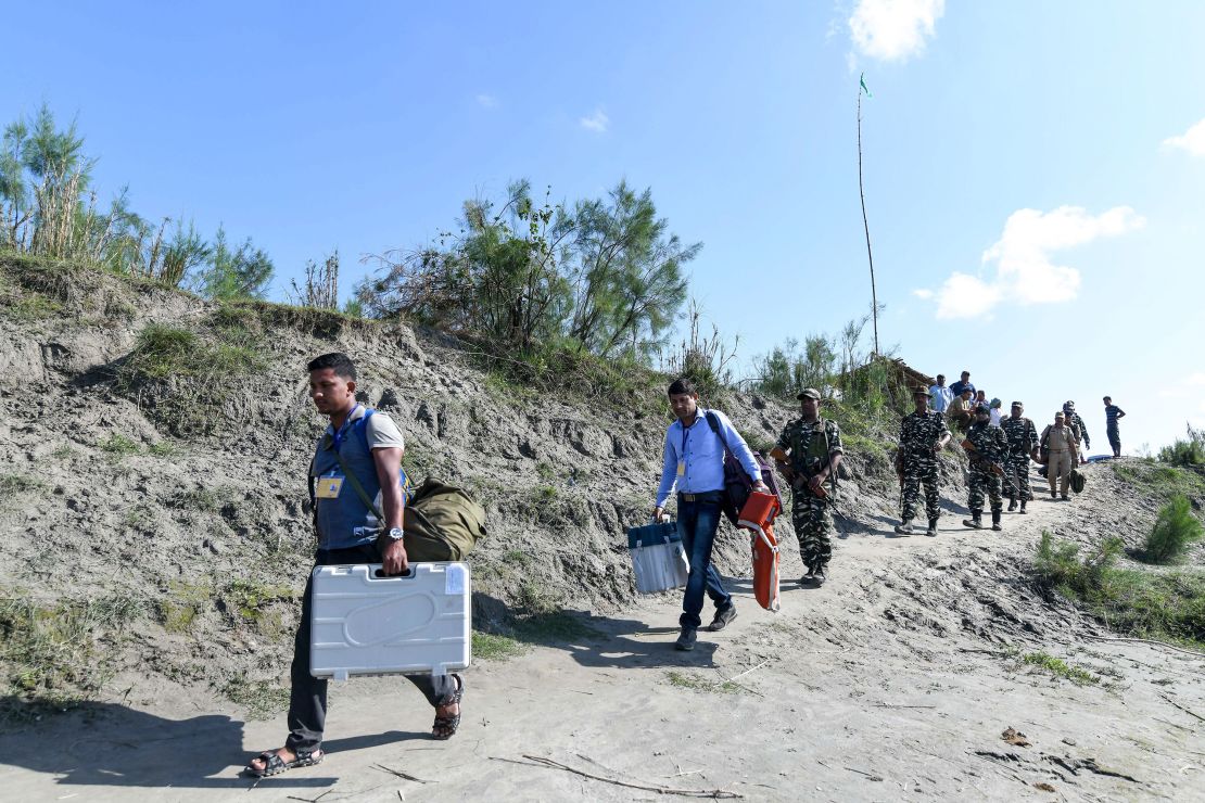 Indian election officials carry Electronic Voting Machines (EVM) and other election material, followed by paramilitary personnel, along the bank of the Brahmaputra river, in Lohore Sapori, some 280 kms from Guwahati in the northeastern state of Assam on April 10, 2019. - India is holding a general election to be held over nearly six weeks starting on April 11, when hundreds of millions of voters will cast ballots in the world's biggest democracy. (Photo by Biju BORO / AFP) (Photo by BIJU BORO/AFP via Getty Images)