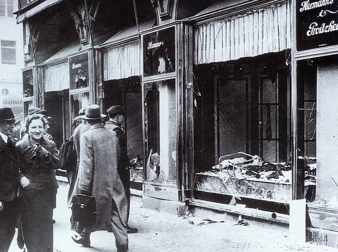 Pedestrians glance at the broken windows of a Jewish owned shop in Berlin after the attacks of Kristallnacht, November 1938.