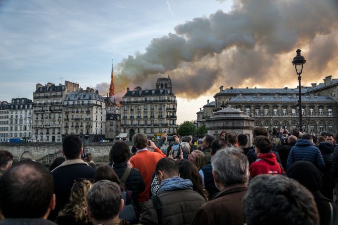 People watch as smoke and flames rise during the fire at the historic monument in central Paris in April 2019.